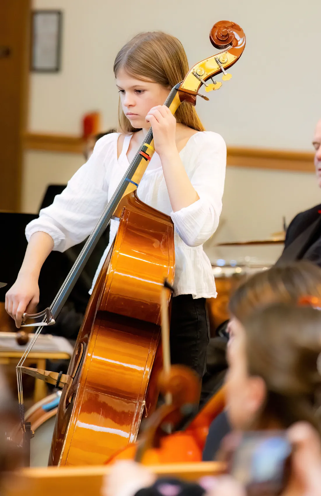 A young bassist playing her double bass with a bow at a concert