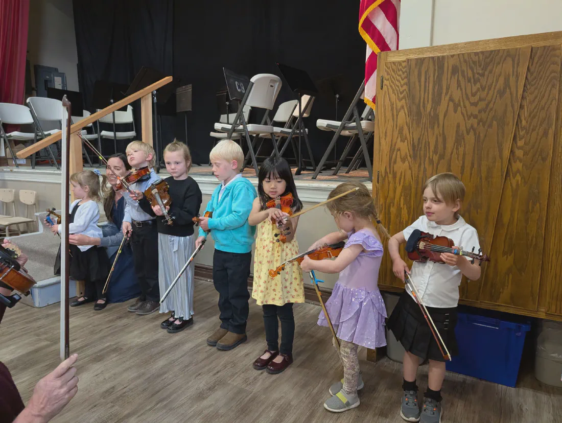 A line of young violinists performing at a concert