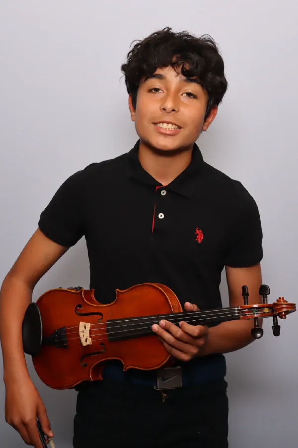 A smiling student holding his violin